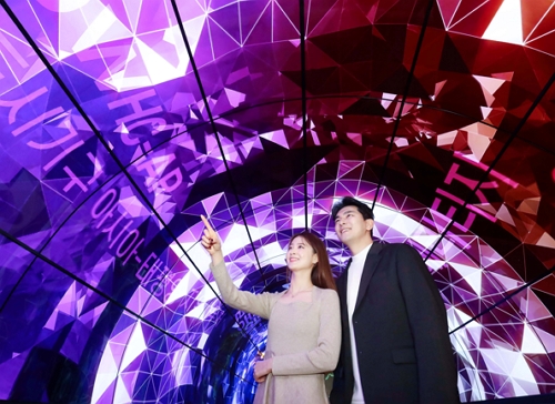 모델들이 55형 올레드 플렉서블 사이니지 72장으로 조성한 10m 길이 올레드 터널에서 미디어 아트를 감상하고 있다. 사진=LG전자