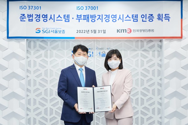 유광열 SGI서울보증 대표이사(왼쪽)가 황은주 한국경영인증원 원장으로부터 준법경영 및 부패방지경영 시스템 인증서를 전달받고 기념촬영을 하고 있다. 사진=SGI서울보증