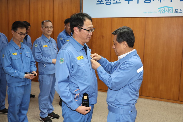 포스코 포항 본사에서 김학동 부회장이 누계 3000시간 이상을 달성한 포항 지역 직원 14명을 대상으로 인증패와 회사 금배지를 수여하고 격려했다. 김학동 부회장 포항제철소 제선부 박희수 과장에게 금배지를 수여하고 있다. (사진=포스코)