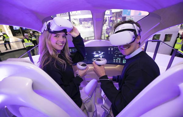 SKT 전시관에서 현지 모델들이 UAM 모형에 탑승해 2030년의 서울을 배경으로 비행하는 서비스를 체험하고 있다. 사진=SKT