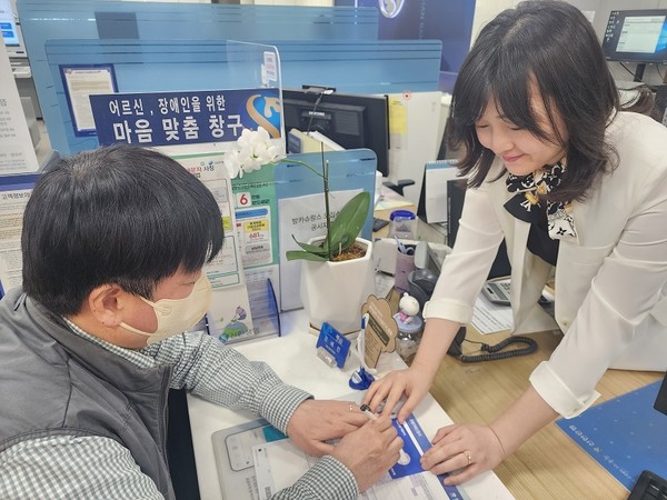 직원이 ‘마음맞춤 응대 KIT’를 활용해 시각장애인 고객과 업무를 보고 있다. 사진=신한은행