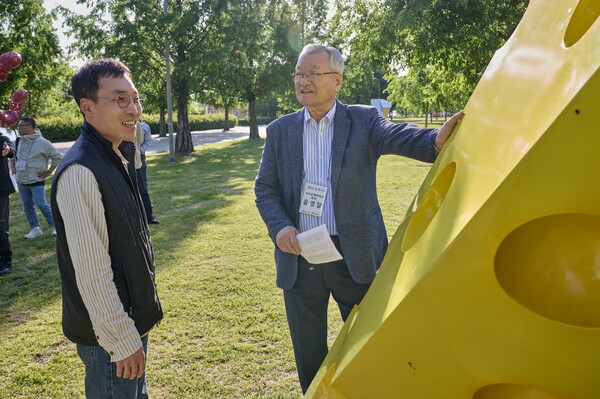 16일 서울 한강뚝섬공원에서 열린 '견생조각전 100회 기념전'에서 윤영달 크라운해태제과 회장이 김정도 작가의 '옮겨진 치즈' 작품에 대한 설명을 듣고 있다. 사진=크라운해태제과