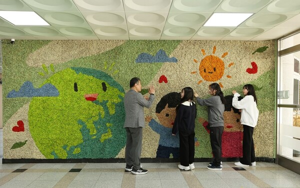 4월 용인 나곡초등학교의 교사와 아이들이 맑은학교 만들기를 통해 조성된 벽면녹화를 살펴보고 있다. 사진=한화