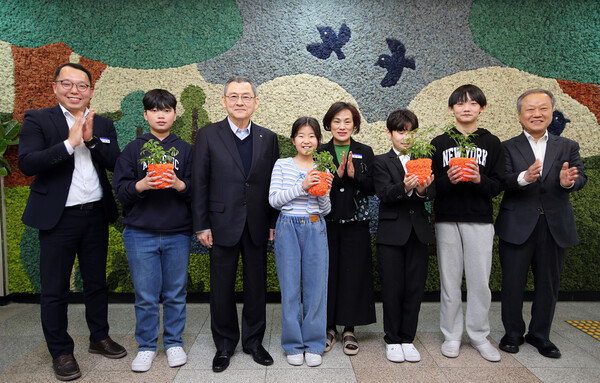 한화 김신연 사장(왼쪽 세번째)이 진잠초 학생들과 함께 공기정화를 위해 한화가 벽면에 조성한 모스월 앞에서 반려 식물을 들고 기념촬영을 하고있다. 사진=한화그룹