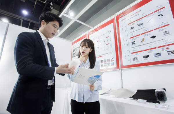 SK케미칼 구성원이 부스에서 폐차 에어백 부품을 해중합 기술로 재활용해 제조된 원료를 들고 순환 재활용 과정을 설명하고 있다. 사진=SK케미칼